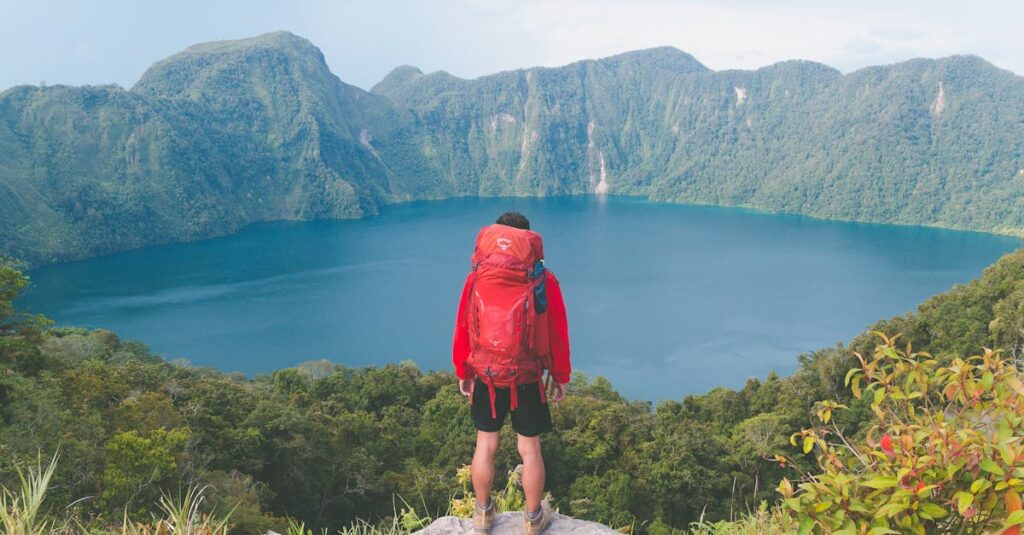 Hiker with backpack enjoying scenic mountain lake view on a bright summer day.